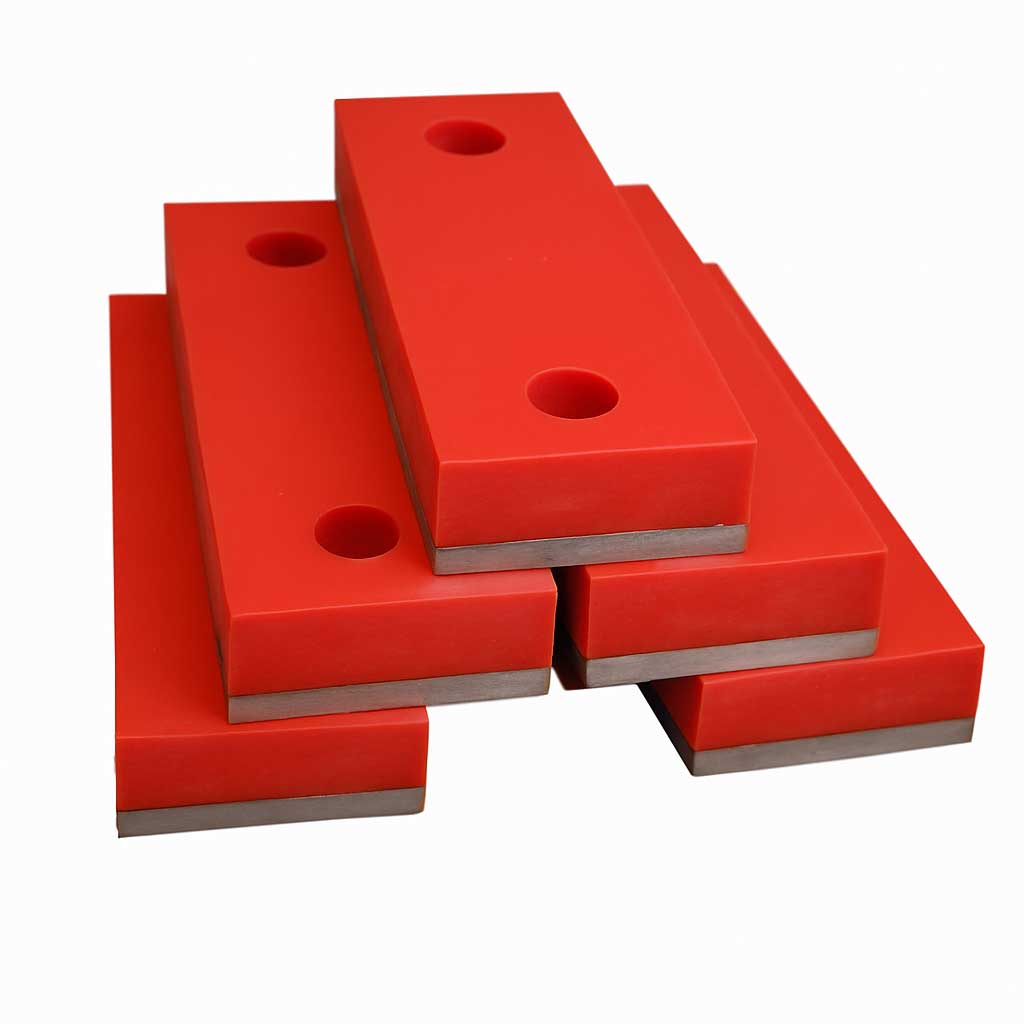 Stack of red urethane impact pads with metal bases engineered by Universal Urethane Products for heavy-duty industrial shock absorption.